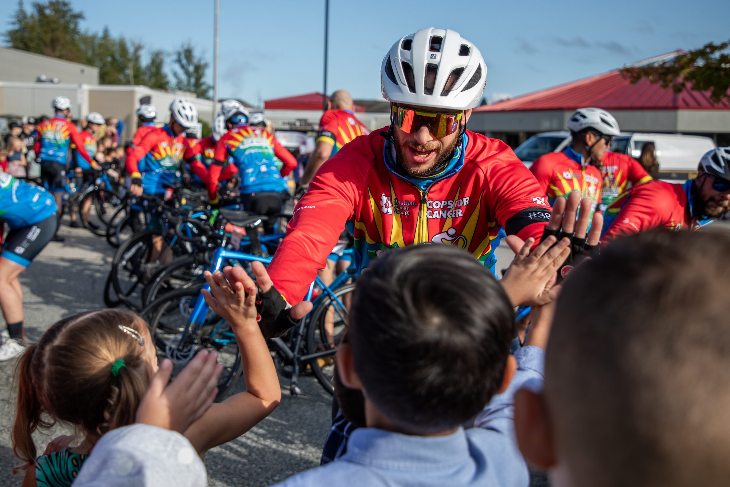 A cyclist with Cops for Cancer Tour de Coast high-fives students at Albion Elementary.