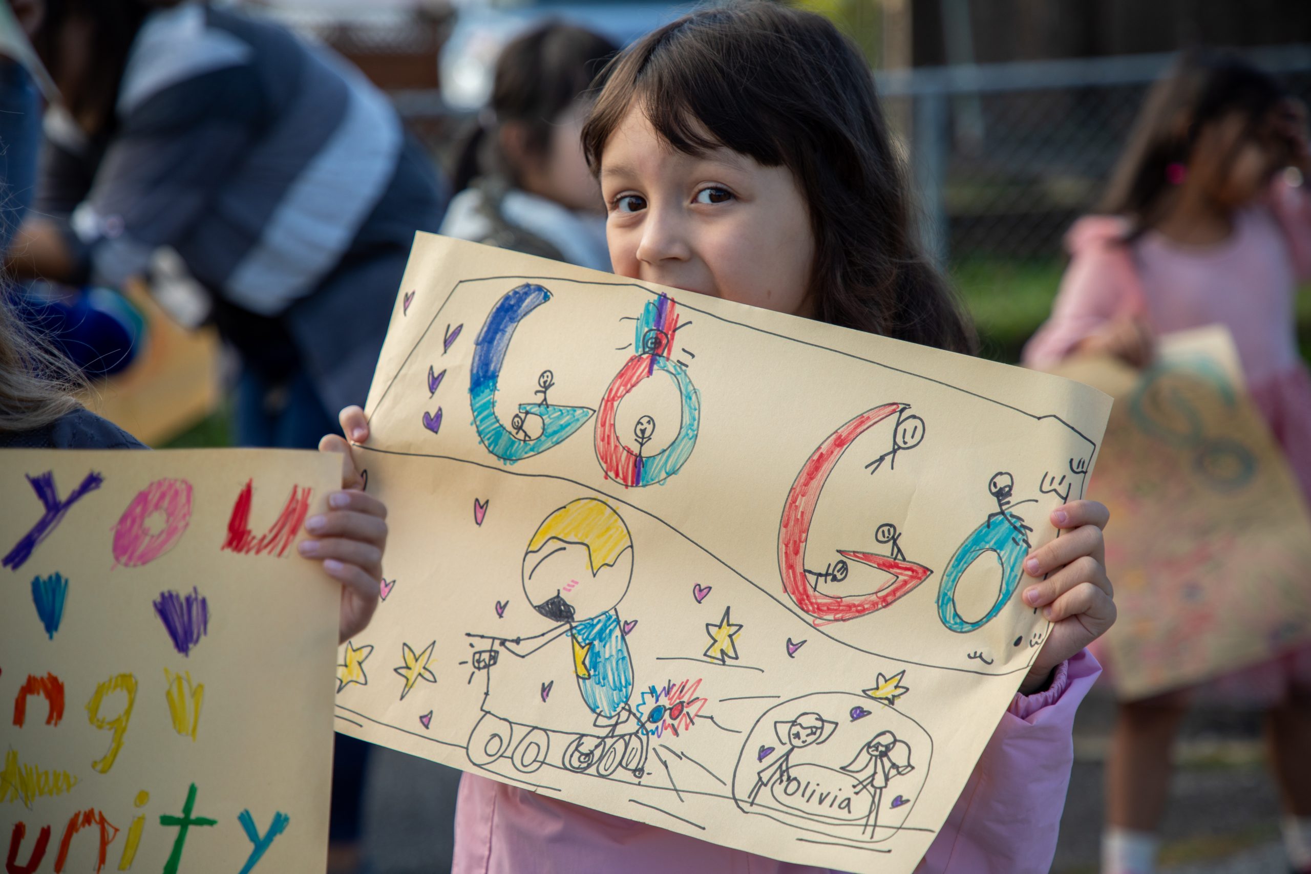 Albion Cops for Cancer-24 Student holds up sign at Albion Elementary cheering on the Cops for Cancer Tour de Coast.