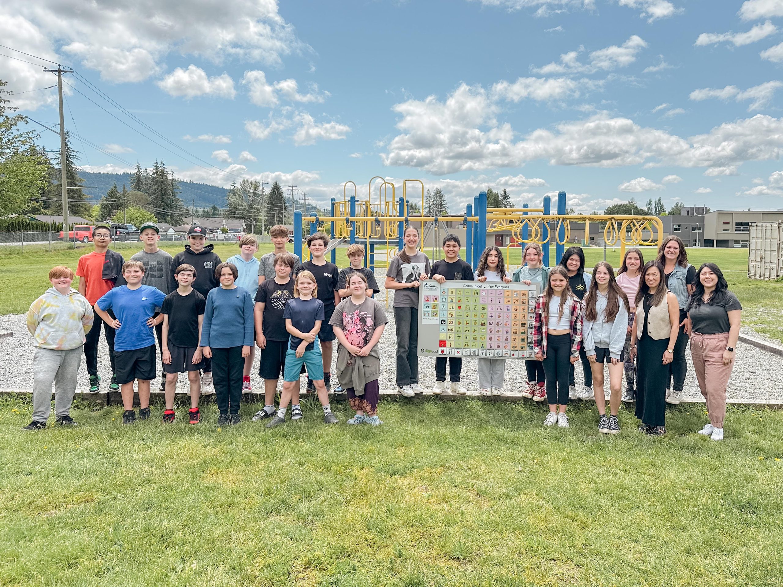 Cassie Tripp's Blue Mountain Elementary class stand in front of a playground with the new communication board.