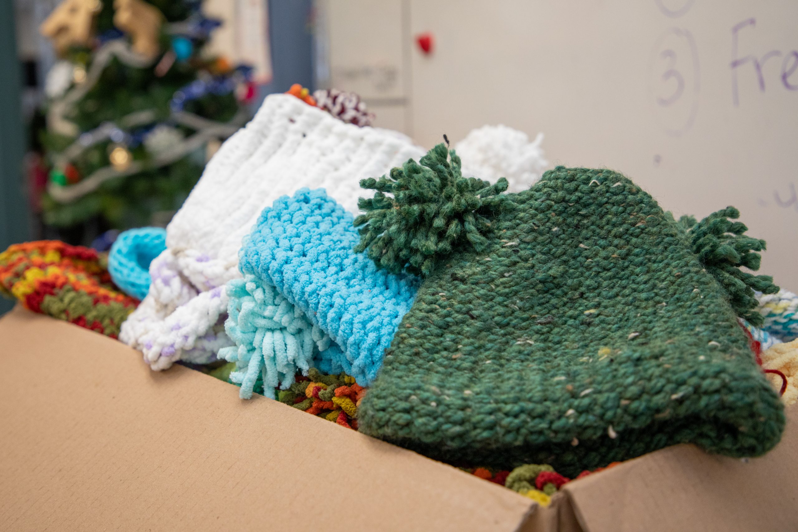 85 hats knitted by Laity View students for donation placed in a cardboard box.